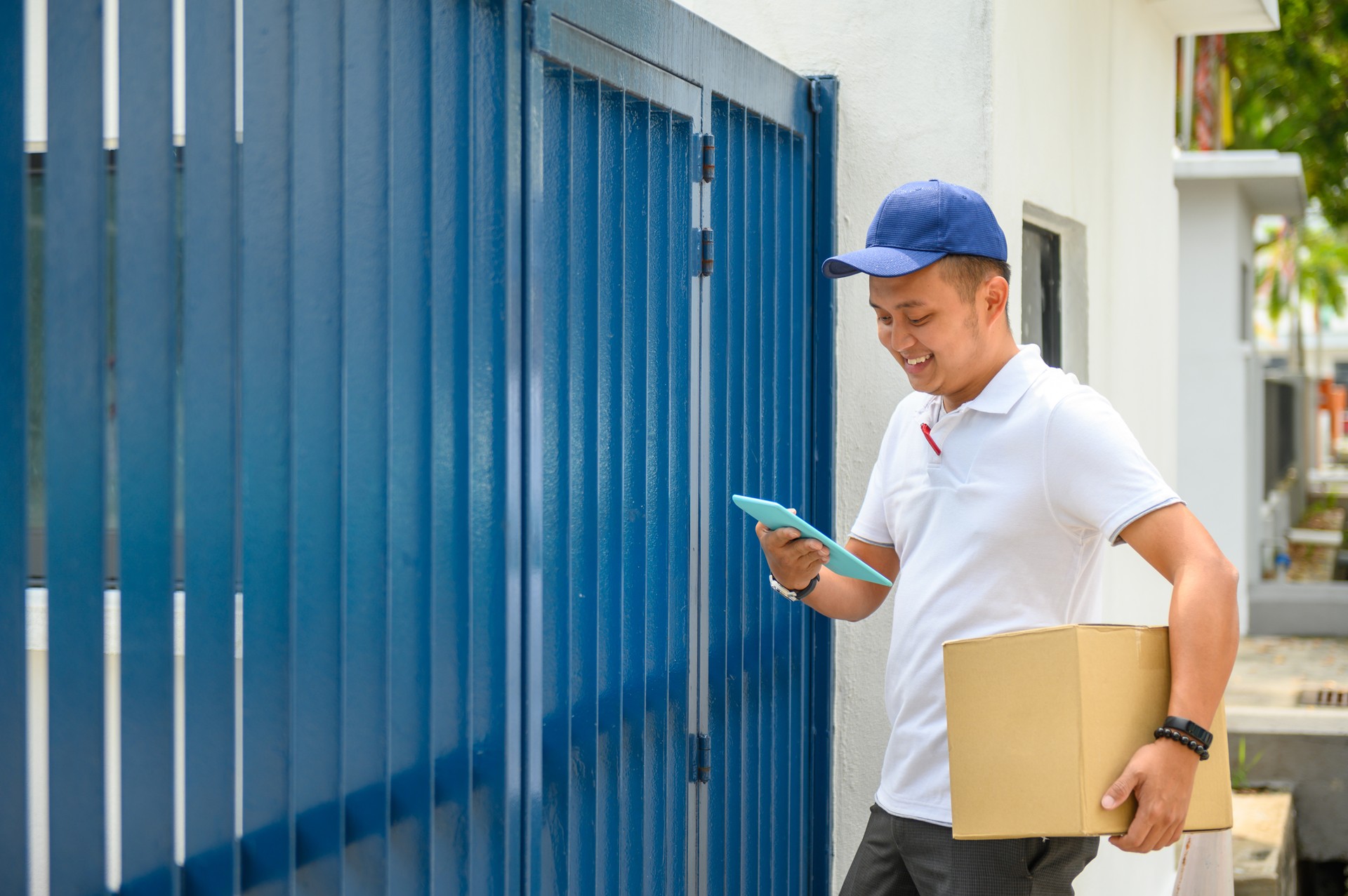 Delivery man holding cardboard box and digital delivery note. COVID-19 outbreak lockdown